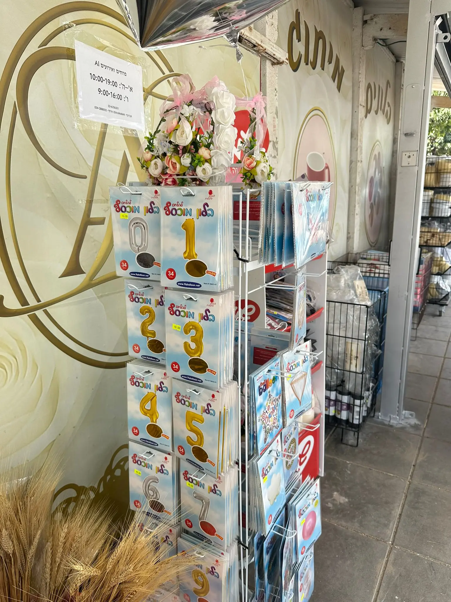 מתלה עם קופסאות בלוני ספרות זהובים וכסופים בכניסה לחנות