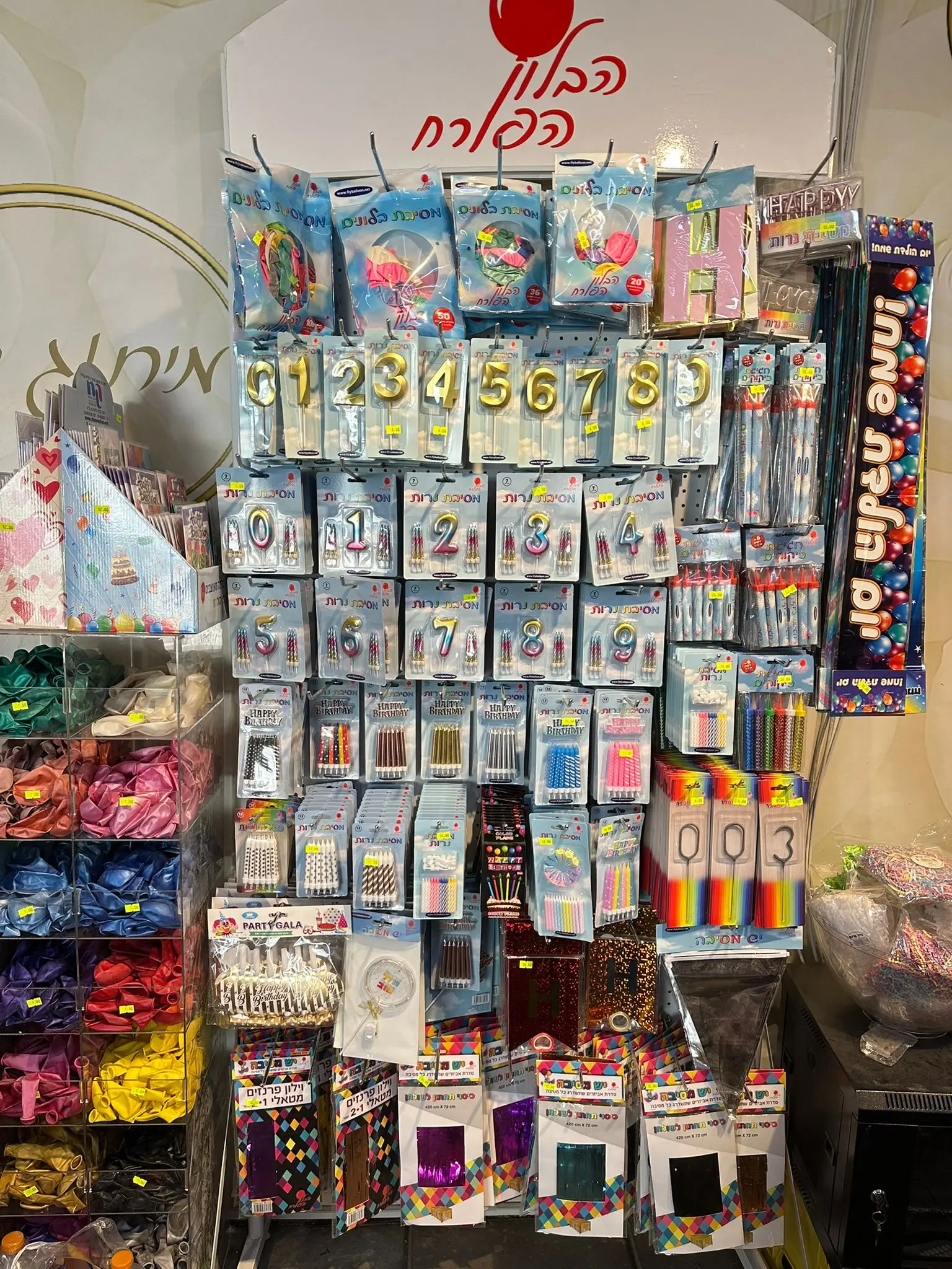 מדף תצוגה עם נרות יום הולדת, ספרות ומוצרי מסיבה